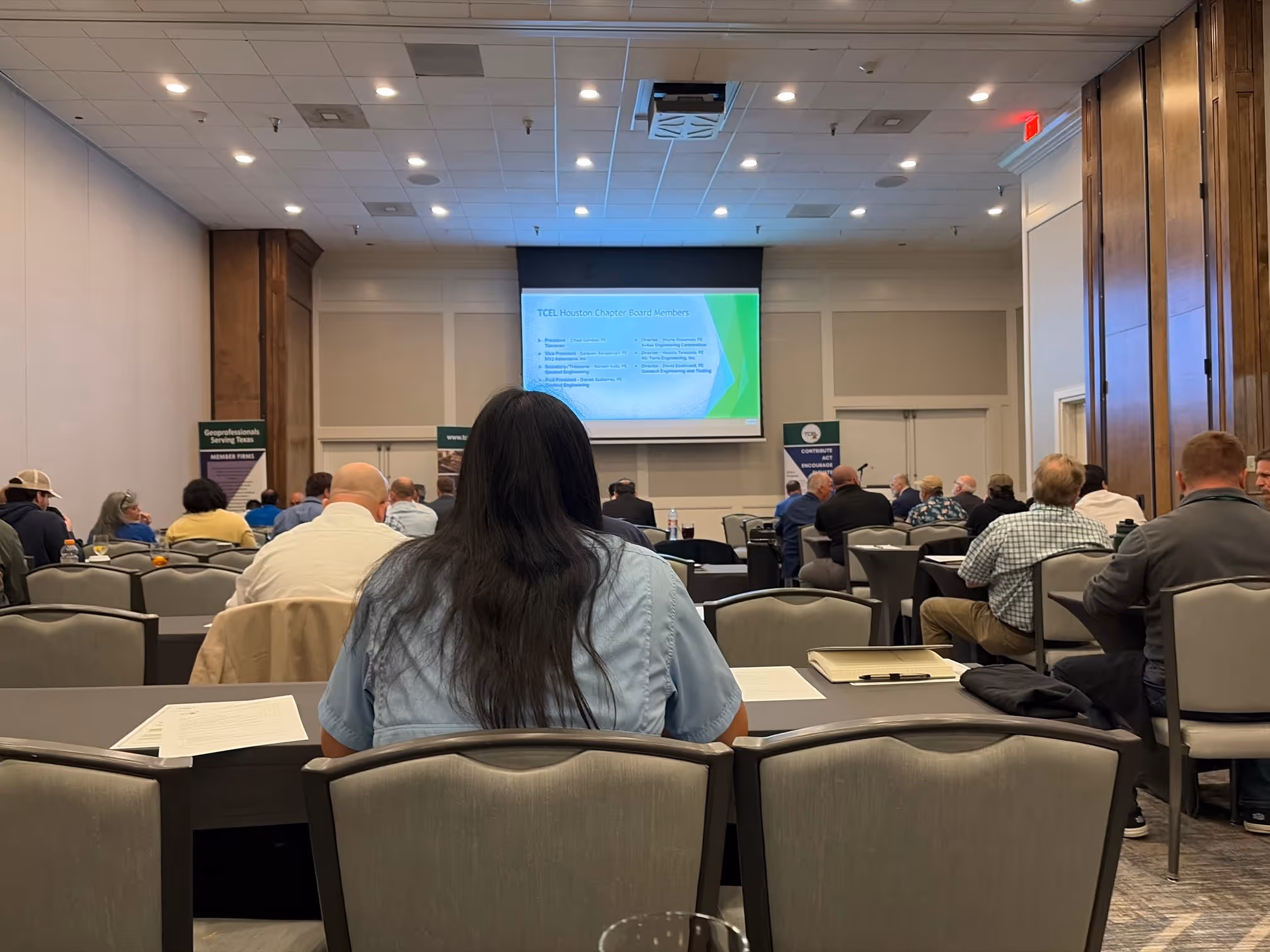 People seated in rows facing a presentation screen in a conference room.